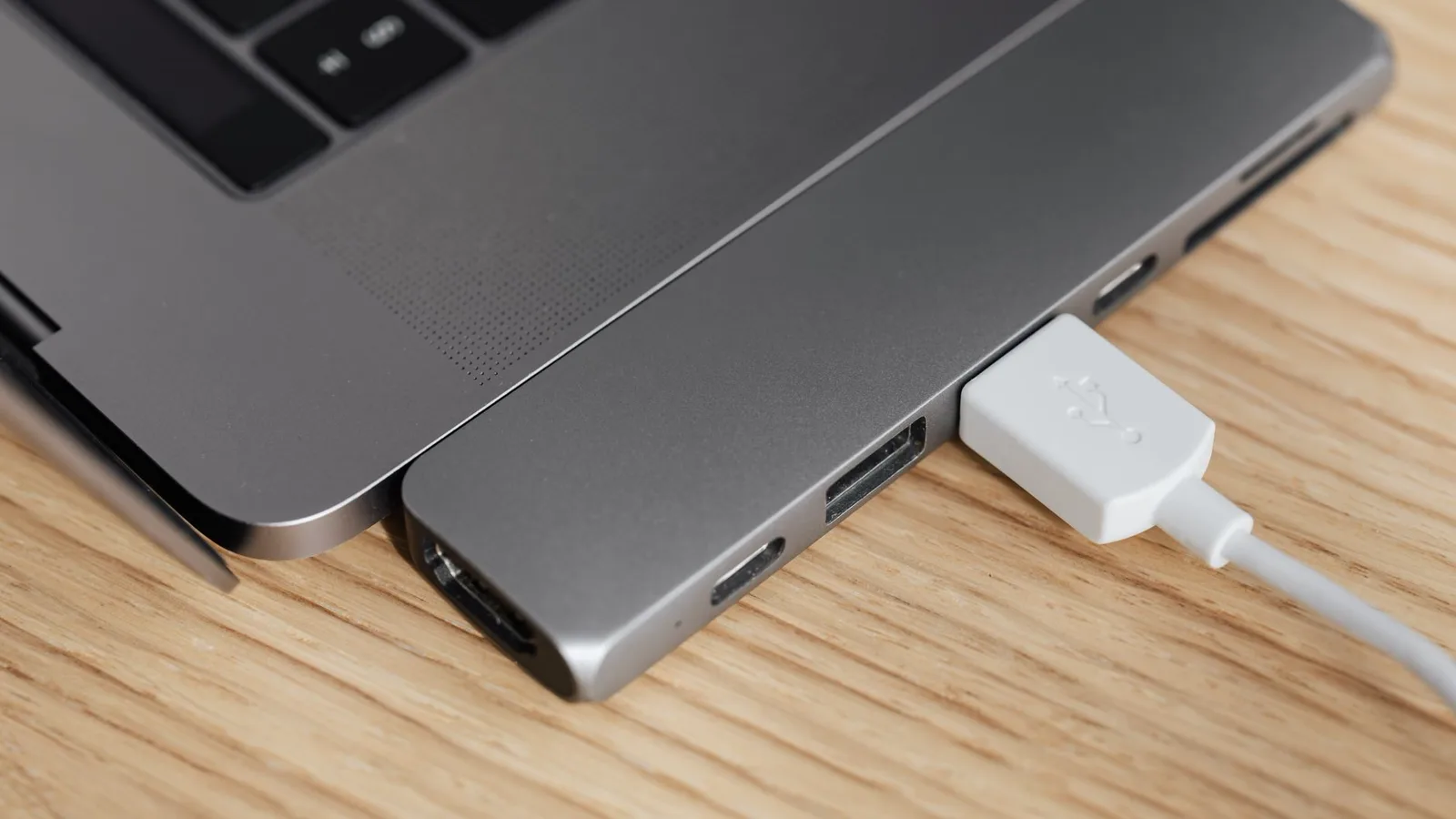 Conversor digital preto compacto em estante de sala, com foco nas portas traseiras HDMI e RCA coloridas, antena simples ao lado, mão apontando para compatibilidade de conexão