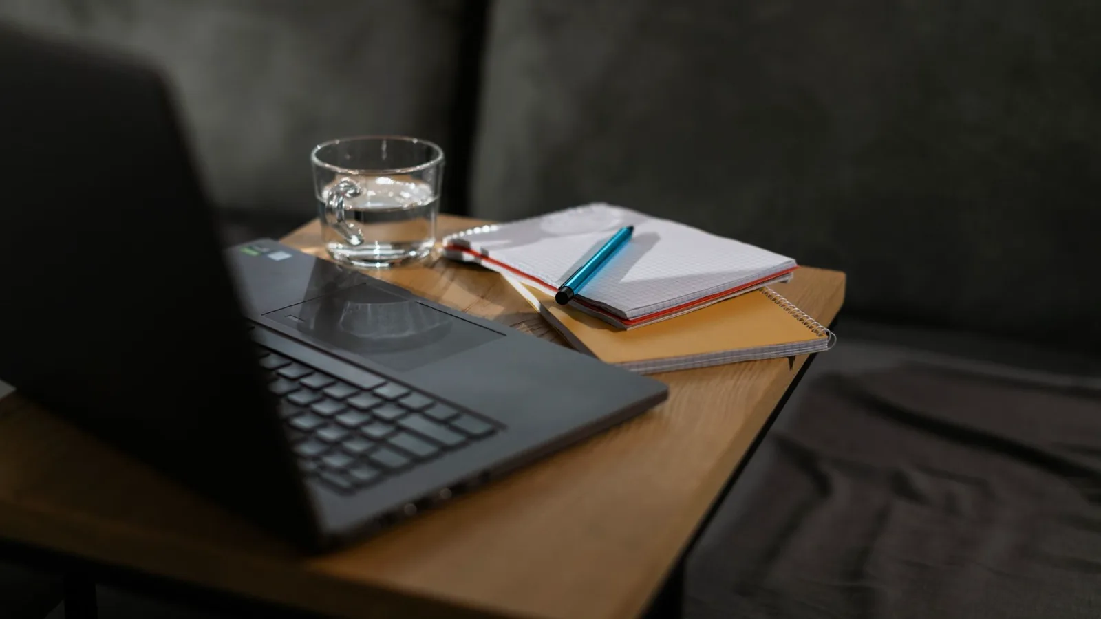 Estação de trabalho montada com docking station: notebook aberto conectado a monitor externo, teclado, mouse e fonte de energia, tudo organizado numa escrivaninha de home office com luz natural.